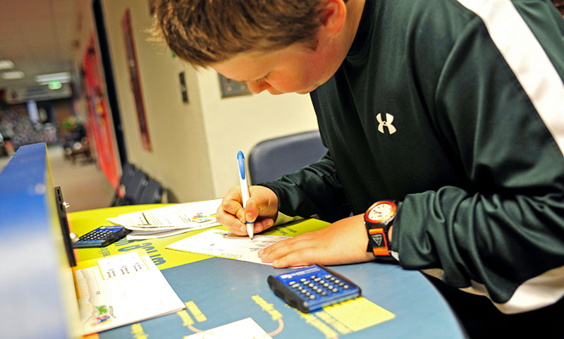 Luke Metzger, 11, fills out his check to pay for his entry onto the Money Bus at DeVaney Elementary School.